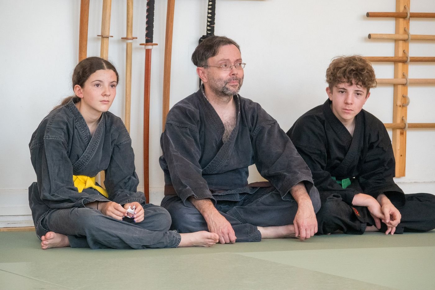 Un enseignant et deux jeunes membres assis sur le tatami, ambiance détendue